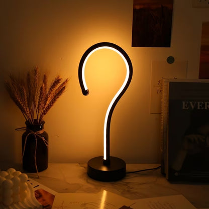 Question mark-shaped lamp on a table with a warm glow